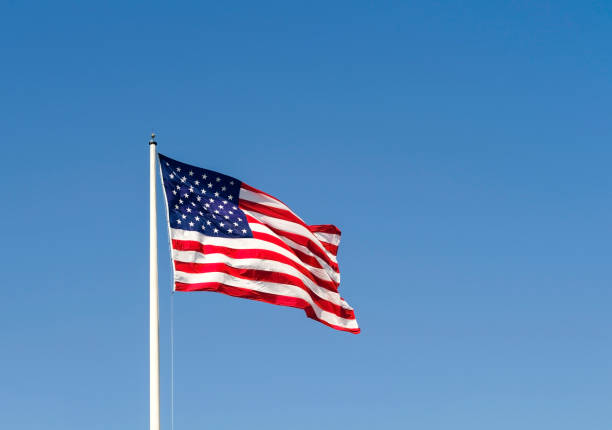 istock American flag waving in the wind against a blue sky. 909157358