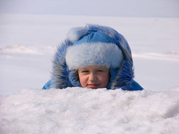 Winter portrait of young girl hiding after snowdrift 