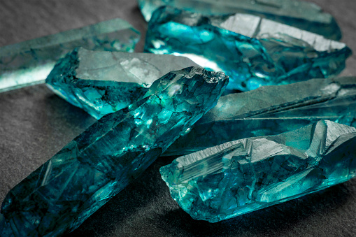 Aquamarines  and raw crystal gems concept with closeup of a bunch of blue uncut aquamarine, topaz or tourmaline crystals