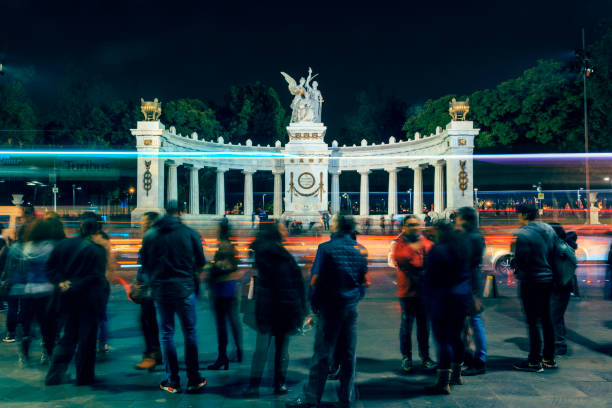 Nocturnal view of the Benito Juarez Monument in the Mexico City downtown. The photo was taken from the other side of the street, so in the first plane you can see the crowd and, a little behind, the lights of traffic on the centric Juarez Avenue.