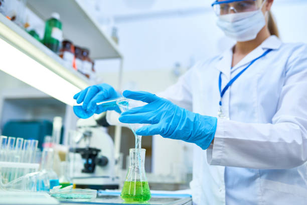 istock Female Scientist Pouring Liquids in Lab 909176618