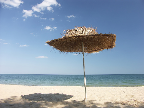 Single straw shade umbrella on a beach