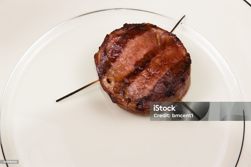 Bacon Wrapped Filet Mignon Bacon wrapped filet mignon steak on cream colored fine china. Burnt Stock Photo