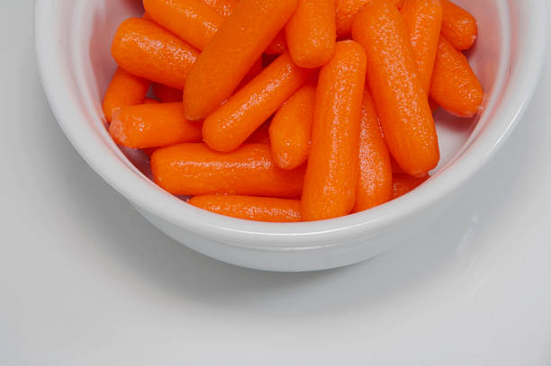 Raw Baby Carrots On White Porceline stock photo