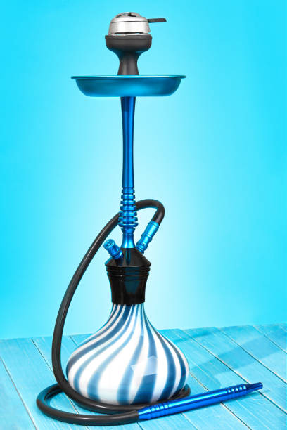 istock Blue hookah with black rubber tube and blue and white flask on light blue background 909191134