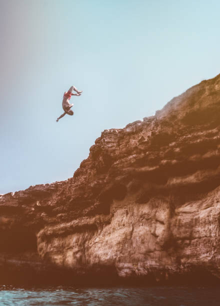 istock Brave cliff diver jumping off rock with somersault into sea 909196654