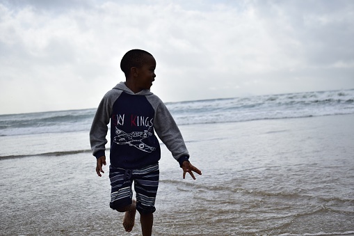 A handsome 12-year-old boy jogs along a beach on the island of Bozcaada in the North Aegean Sea on a sunny morning.