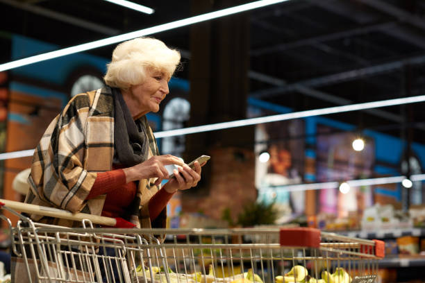 istock Senior Woman Using Smartphone in Supermarket 909197012