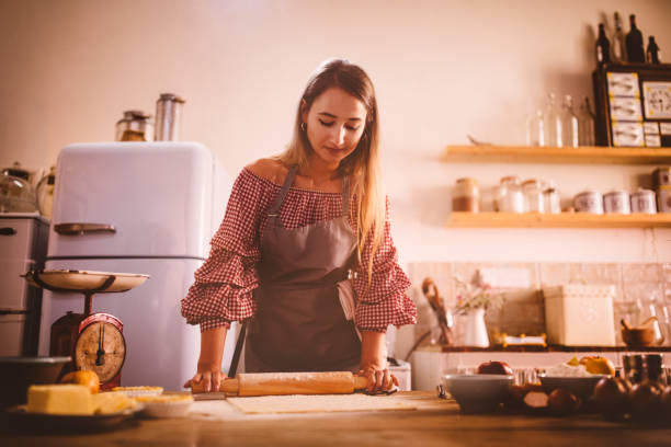 istock Woman baking and rolling dough with rolling pin in kitchen 909199696