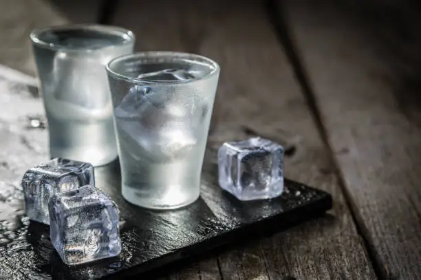 Photo of Vodka in shot glasses on rustic wood background