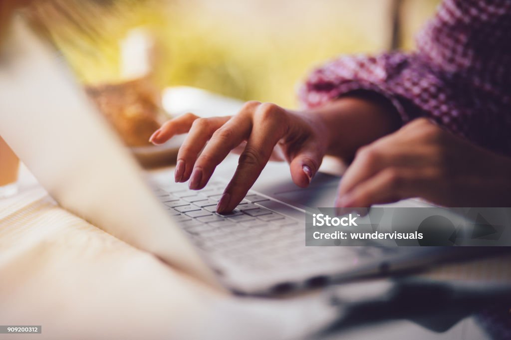 Close-up of woman's hands typing on laptop keyboard Close-up of female freelancer's hands typing on keyboard and working on laptop from home office Writing - Activity Stock Photo