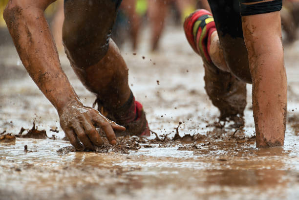 Mud race runners Crawling,passing under a barbed wire obstacles during extreme obstacle race obstacle course stock pictures, royalty-free photos & images