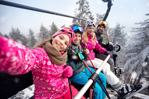 Familia feliz en teleférico subir a terreno de esquí photo