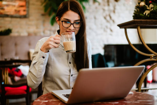istock Beautiful long haired girl drinking coffee while looking at laptop. 909203542
