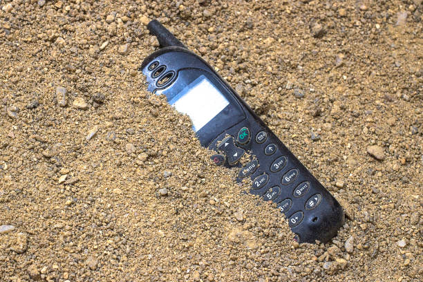 istock Mobile phone buried in the grey sand 909204564