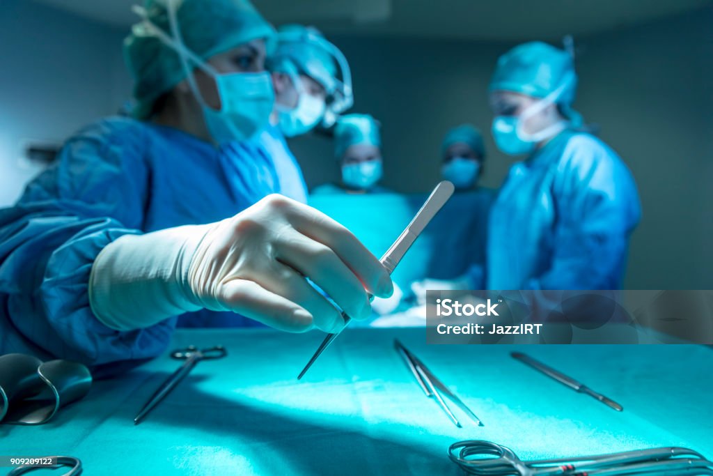 Surgeons in full surgical gear during operation Scalpel Stock Photo