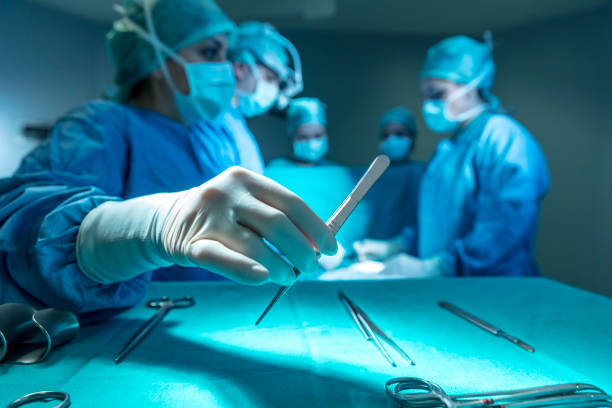 Surgeons in full surgical gear during operation Surgeons in full surgical gear during operation scalpel photos stock pictures, royalty-free photos & images