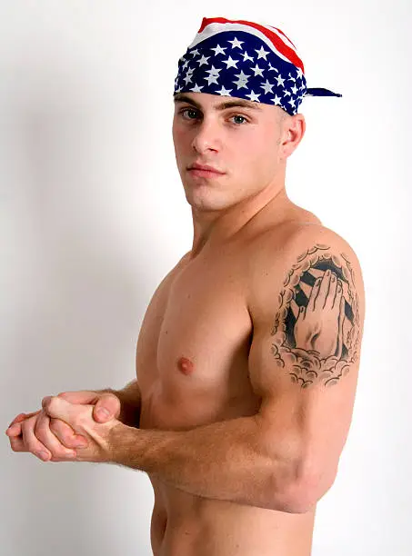 Barechested, muscular man wearing a do=rag and holding a hard hat