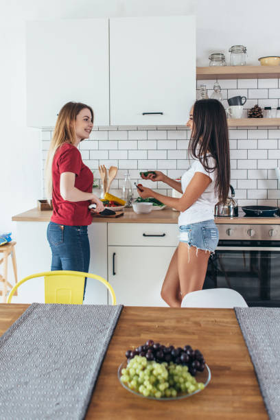 istock Two women in kitchen cooking talking preparing food. 909217366