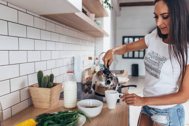 istock Woman pouring boiling water into a cup from kettle. 909220118