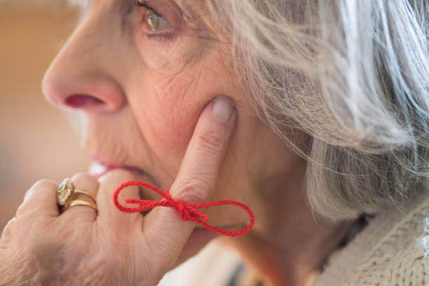 gros plan d’une femme senior avec chaîne nouée autour du doigt comme rappel - residential care photos photos et images de collection