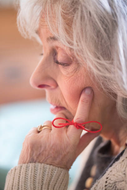 close up of senior woman with string tied around finger as reminder - reminder memories human finger string imagens e fotografias de stock