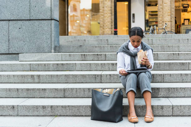 istock Businesswoman eating  sandwich and using digital tablet 909232226