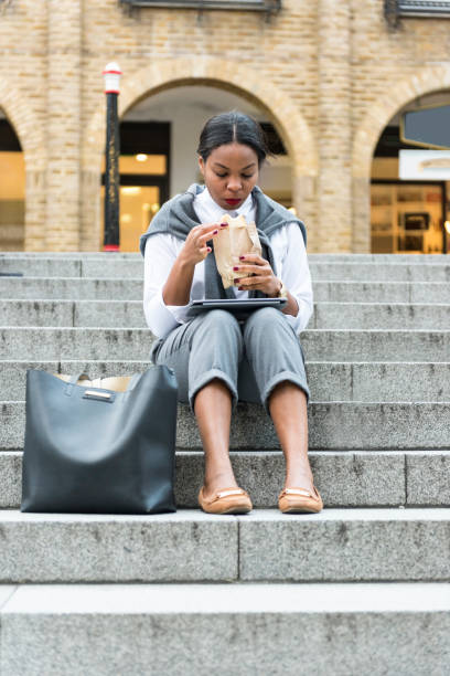 istock Businesswoman eating  sandwich and using digital tablet 909232274