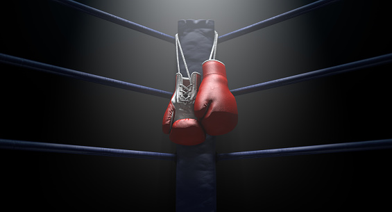 The blue corner of a boxing ring with gloves hanging on a pole spotlit on an isolated dark background - 3D render