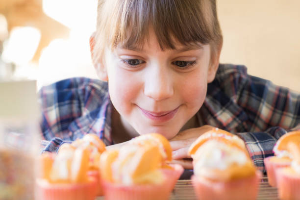 istock Girl Looking Hungrily At Home Made Cup Cakes 909235406