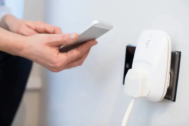 Photo of Woman Controlling Smart Plug Using App On Mobile Phone