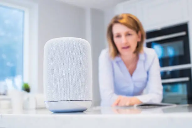 Photo of Woman In Kitchen Asking Digital Assistant Question