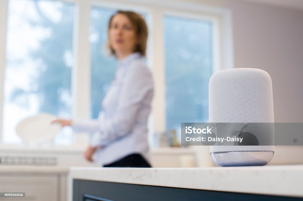Woman In Kitchen Asking Digital Assistant Whilst Washing Up Virtual Assistant Stock Photo