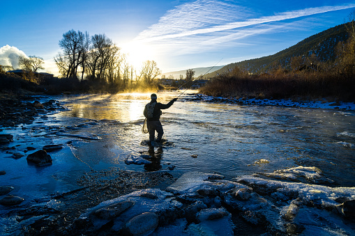Fly Fisherman Winter Fishing - Scenic and cold Eagle River with man recreating in very cold temperatures.