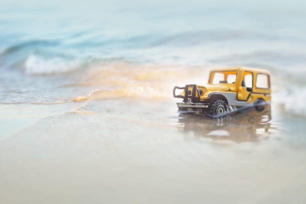 istock Car  (miniature, toy model ) crossing the sea with splashing water. 909250024