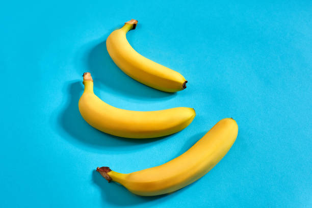 istock Fresh bananas close up on bright blue background. Flat lay. Summer concept 909252558