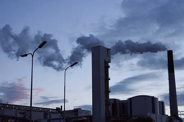 Sugarbeet factory with smoking chimney at dawn