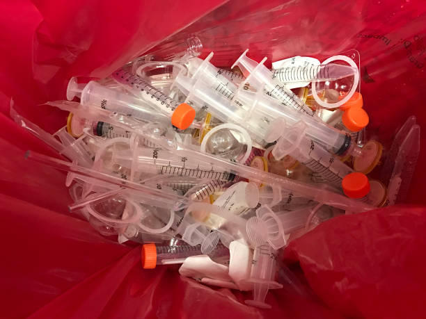 Medical hazardous laboratory waste In an HIV testing laboratory, single-use plastic syringes, pipettes, and filters are disposed of in a red hazardous materials waste bag. toxic waste stock pictures, royalty-free photos & images