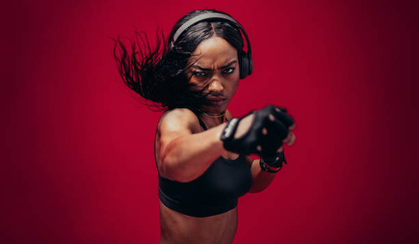 Boxer practicing her punches in a studio Boxer practicing her punches in a studio. African female boxer practicing boxing against red background. toughness photos stock pictures, royalty-free photos & images
