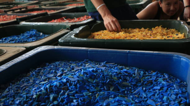 Recycled Plastic Pieces Tiny bits of recycled plastic in a bins in trash management facility in Ghana. They are colorful chips in giant trash bins, in a recycling center. recycling center stock pictures, royalty-free photos & images