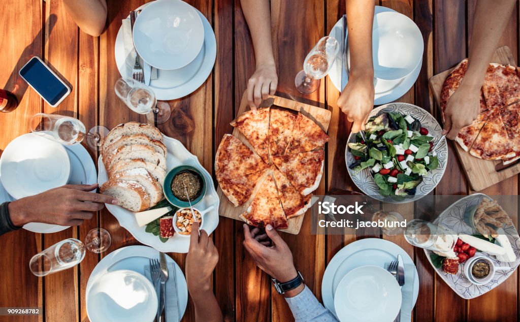 Friends having pizza at party Top view of group of friends having food and drinks. Enjoying the food at housewarming party. Pizza Stock Photo