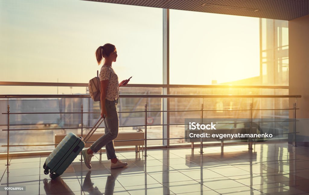 junge Frau geht am Flughafen am Fenster mit Koffer Flugzeug wartet - Lizenzfrei Flughafen Stock-Foto