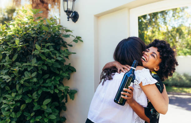 mujer con amigo felicitando a botella de vino para casa nueva - abrazar las rodillas fotografías e imágenes de stock