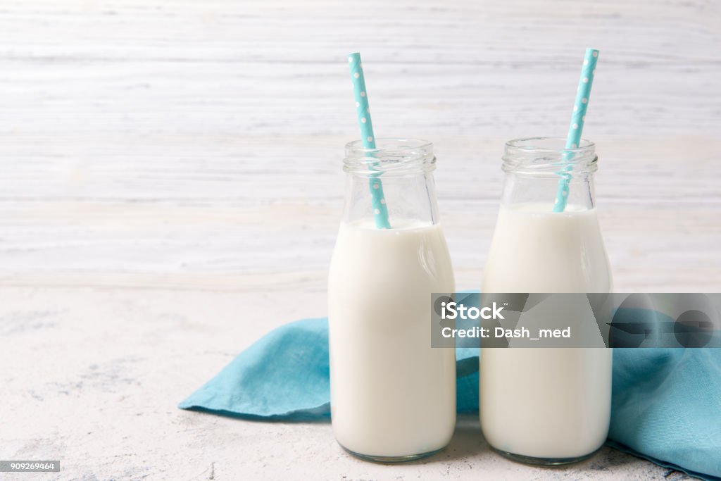 Two bottles of milk with blue straws on wooden background Two bottles of fresh milk with blue straws on wooden background Milk Stock Photo