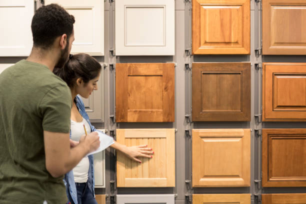 Young couple look at cabinet samples in home improvement store Couple look at cabinet samples in a hardware store. The woman touches one of the cabinet samples. The man is taking notes. cupboard stock pictures, royalty-free photos & images