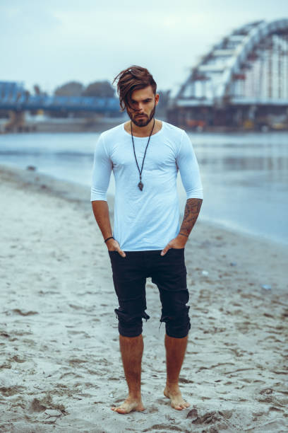 istock Young man posing on the sand by the river 909272364