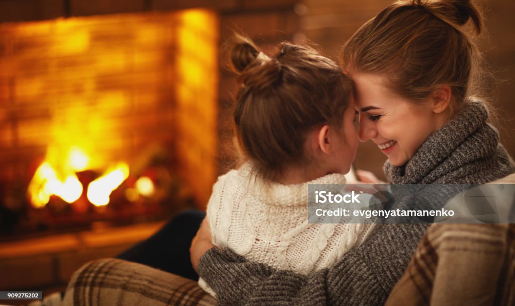 abrazos familia de la madre y el niño y riendo en noche de invierno junto a chimenea - Foto de stock de Familia libre de derechos