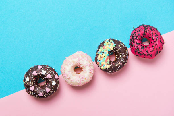 istock Assorted colored donuts in a row, minimalism on a blue and pink background, top view 909275690