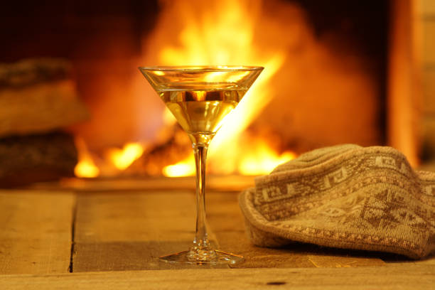 istock Glass martini against cozy fireplace background, winter vacation. 909287884