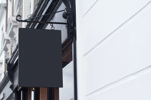 Horizontal side view of empty black square signage on a British building with classical architecture